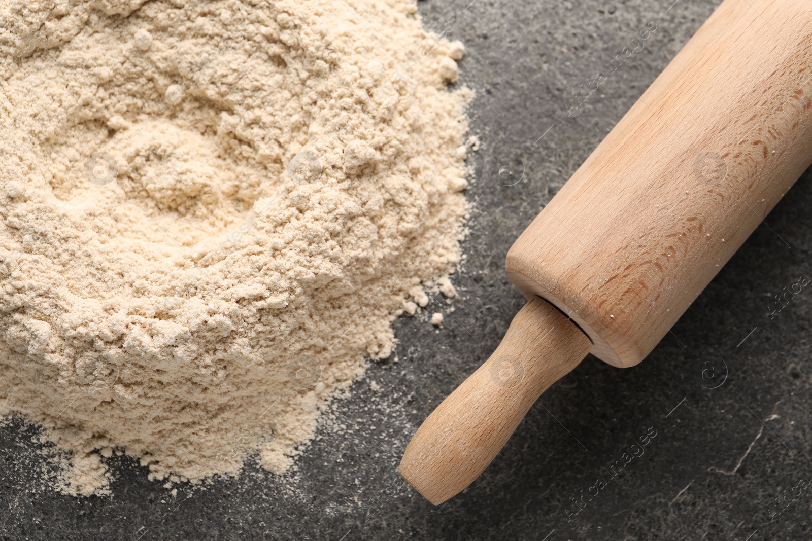 Photo of Pile of flour and rolling pin on grey textured table, top view