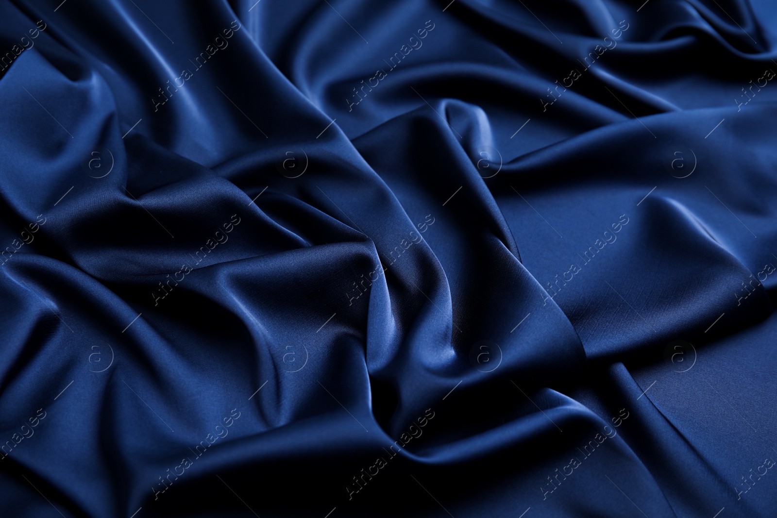 Photo of Crumpled dark blue silk fabric as background, closeup