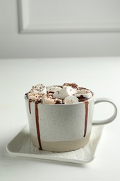 Photo of Delicious hot chocolate with marshmallows and cocoa powder in cup on white table
