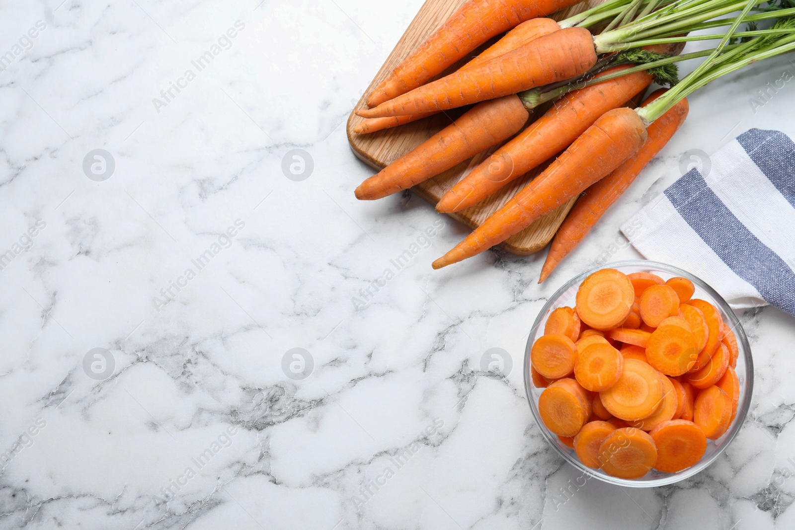 Photo of Whole and cut ripe carrots on white marble table, flat lay. Space for text