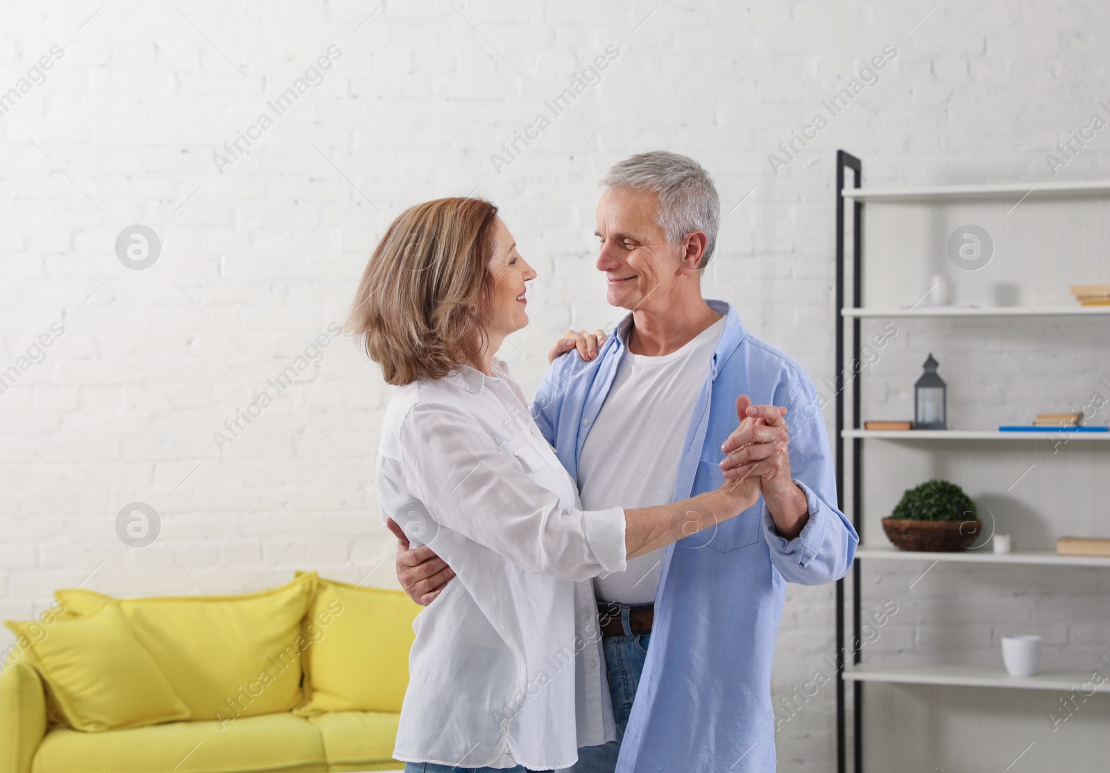 Photo of Happy senior couple dancing together in living room