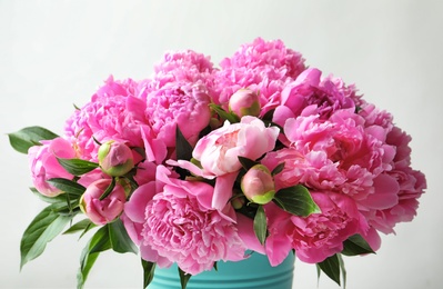 Bucket with beautiful peony flowers on light background