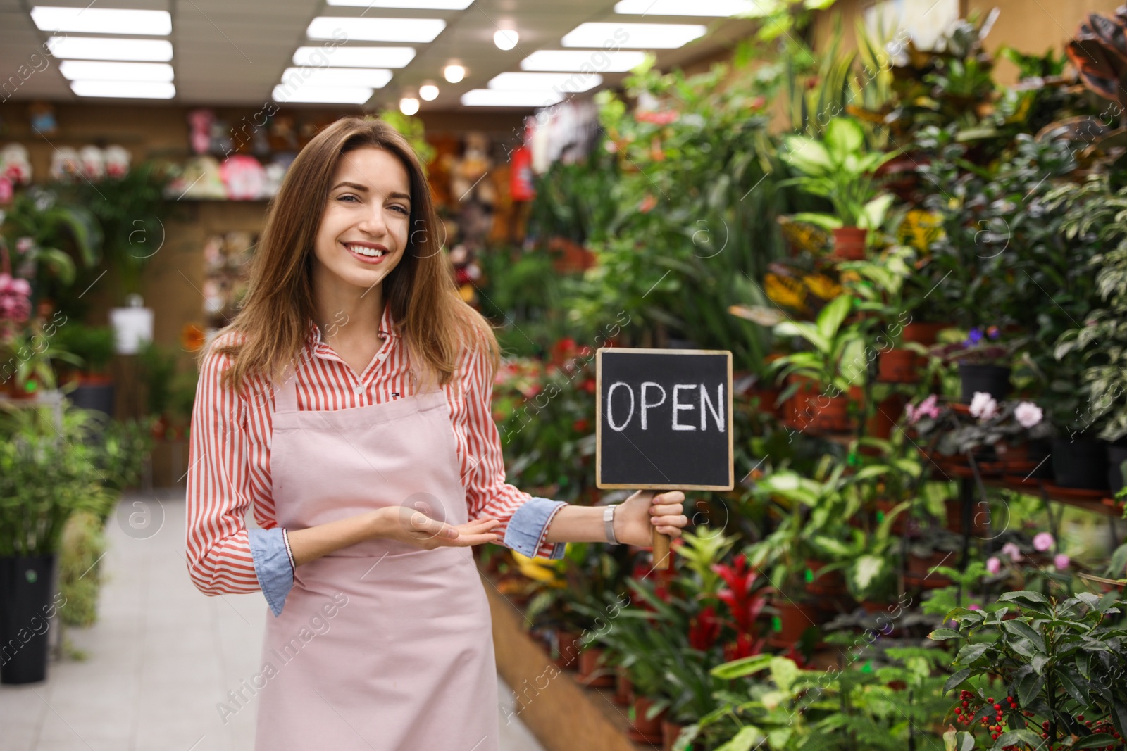 Photo of Young business owner holding OPEN sign in flower shop