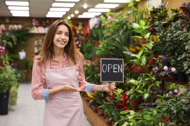 Young business owner holding OPEN sign in flower shop
