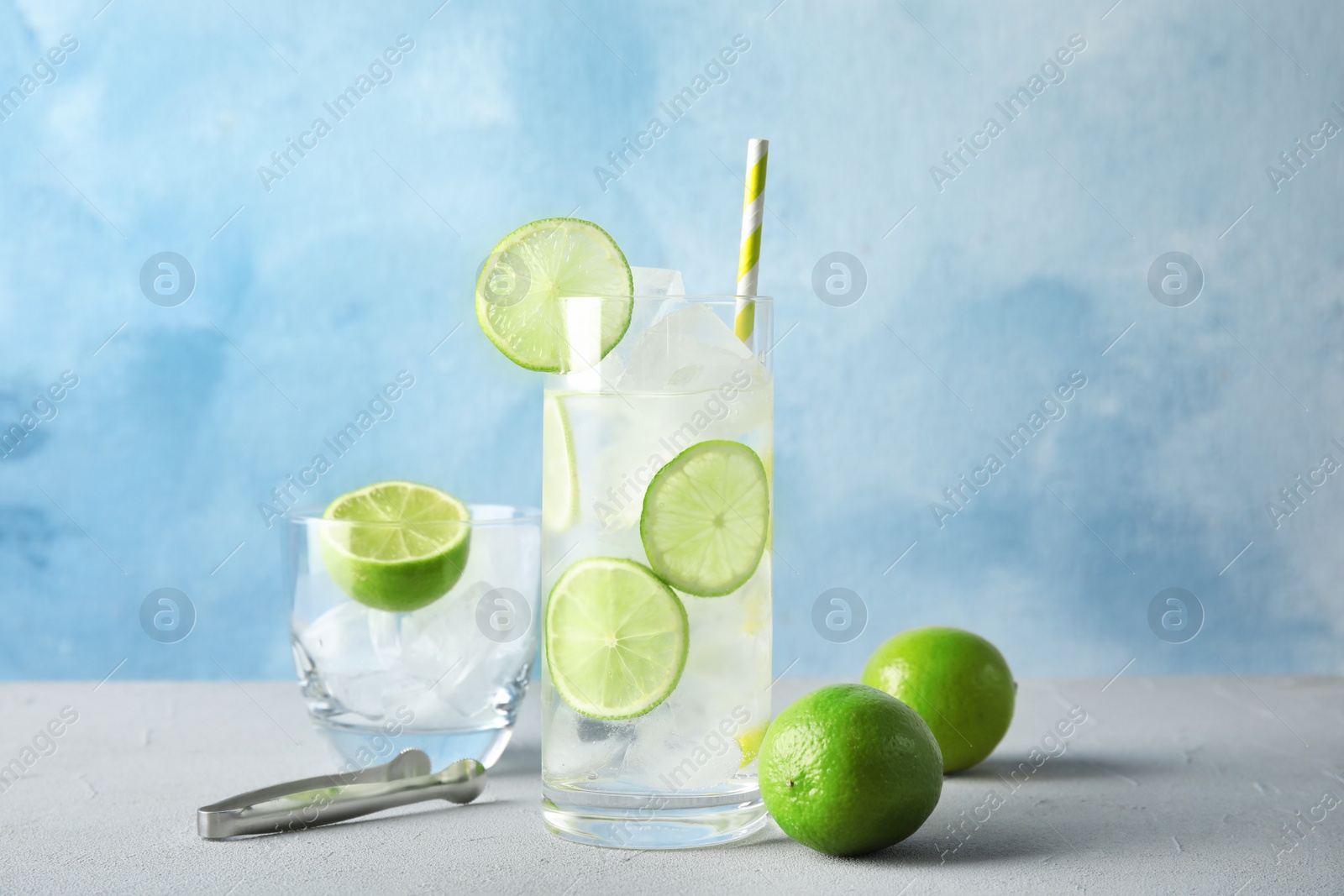 Photo of Composition with lime drink and ice cubes in glass on table against color background