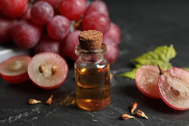 Photo of Bottle of natural grape seed oil on dark table. Organic cosmetic