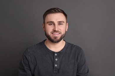 Portrait of happy young man on grey background. Personality concept