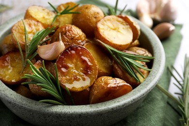 Photo of Tasty baked potato and aromatic rosemary in bowl on table, closeup