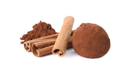 Photo of Delicious chocolate truffle with cocoa powder and cinnamon sticks on white background