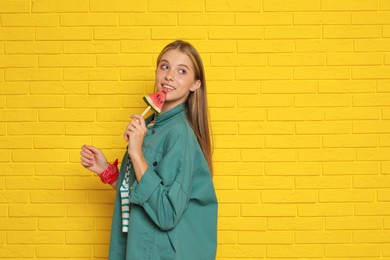 Photo of Beautiful girl with piece of watermelon near yellow brick wall. Space for text