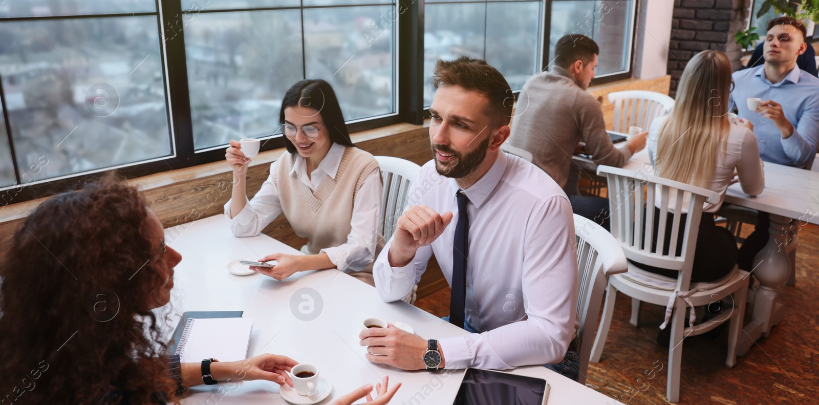 Image of Coworkers having coffee break near window in cafe. Banner design