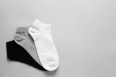 Different socks on light grey background, flat lay. Space for text