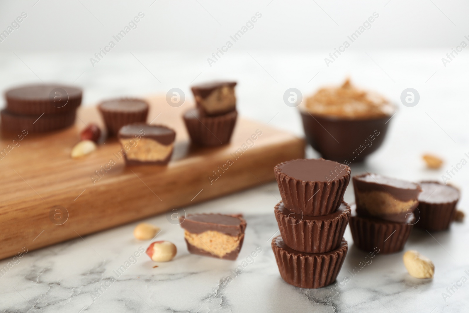 Photo of Delicious peanut butter cups on white marble table, space for text