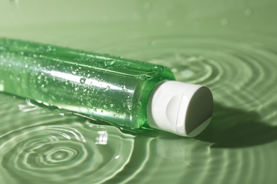 Bottle of micellar water in liquid on green background