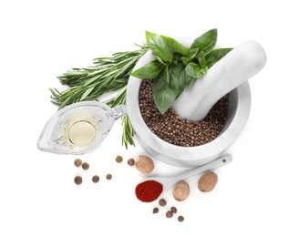 Mortar with pestle and different spices on white background, top view