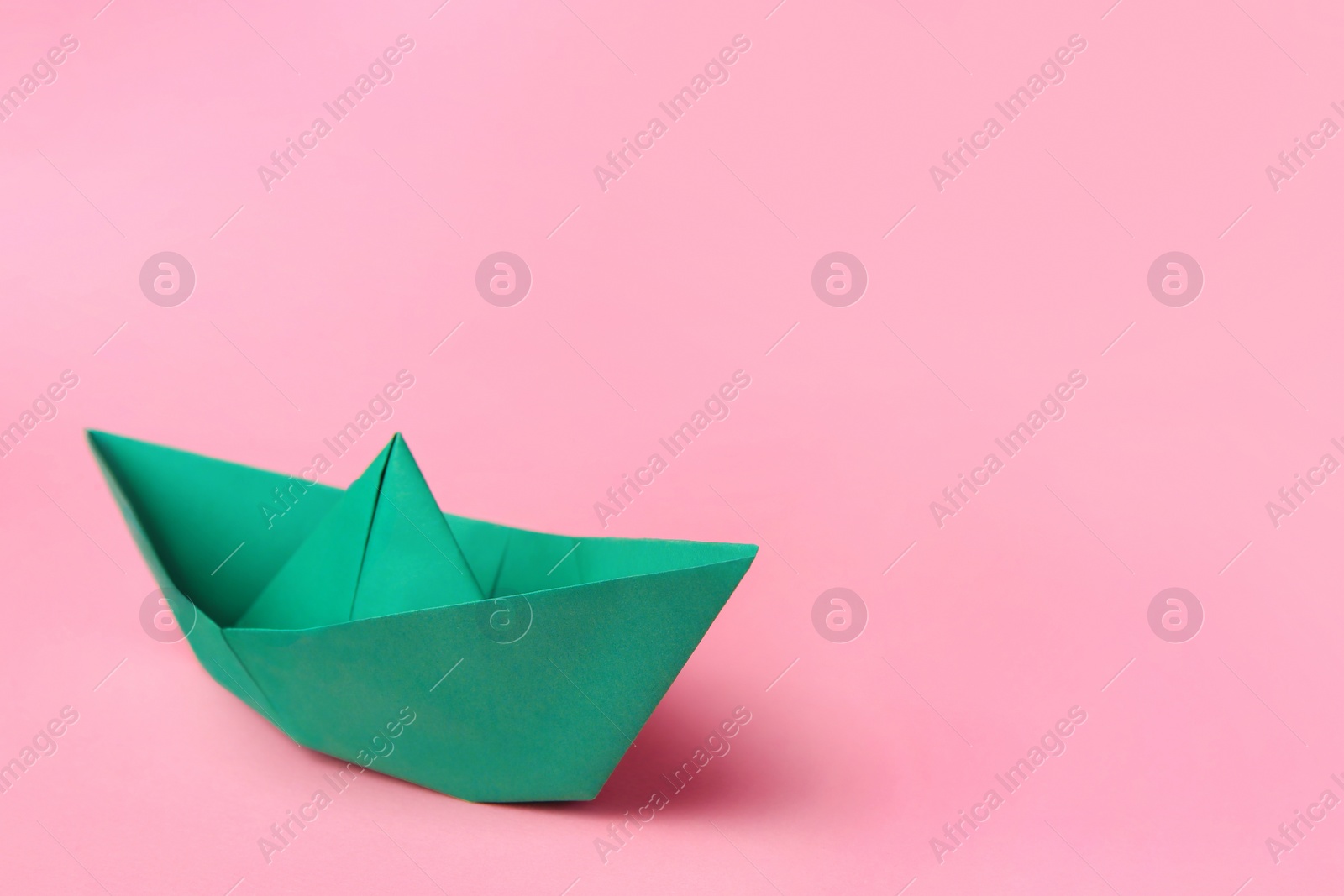 Photo of Origami art. Paper boat on pink background, space for text