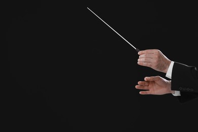 Photo of Professional conductor with baton on black background, closeup. Space for text