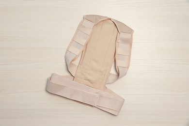 Photo of Beige posture corrector on white wooden table, top view