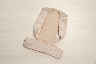 Beige posture corrector on white wooden table, top view