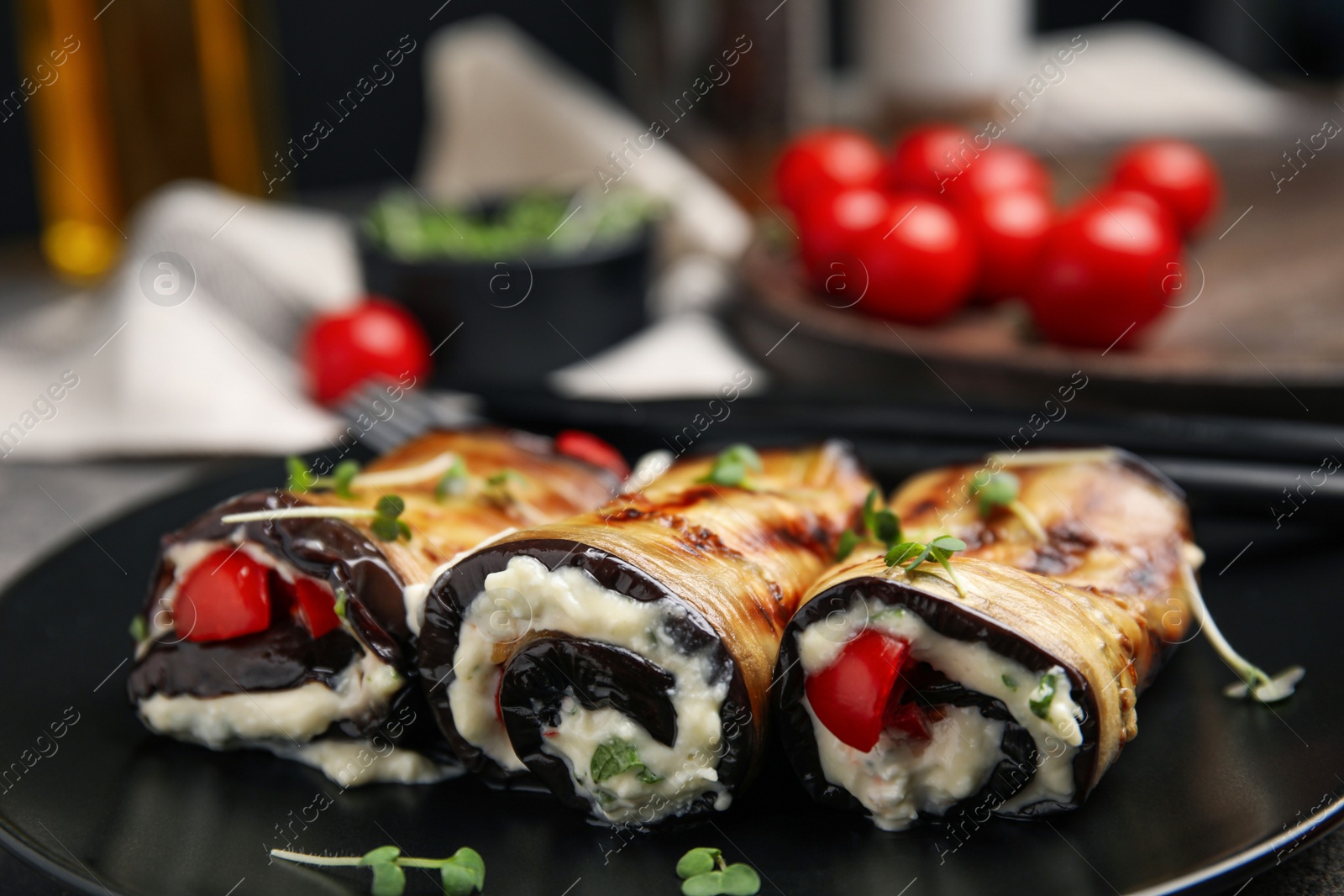 Photo of Delicious baked eggplant rolls with cheese, tomatoes and microgreens on plate, closeup