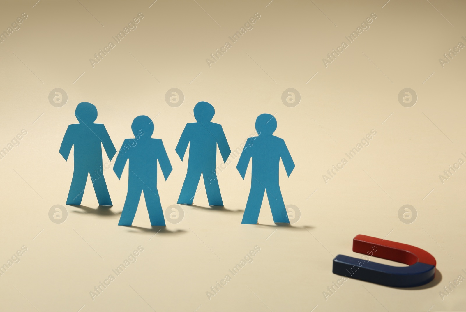 Photo of Magnet attracting paper people on beige background