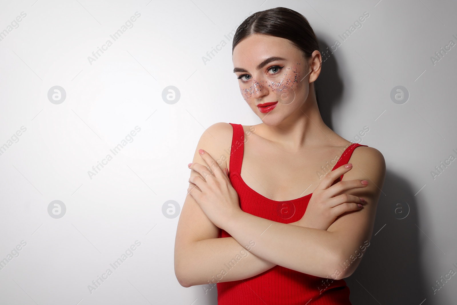 Photo of Beautiful woman with glitter freckles on light background. Space for text