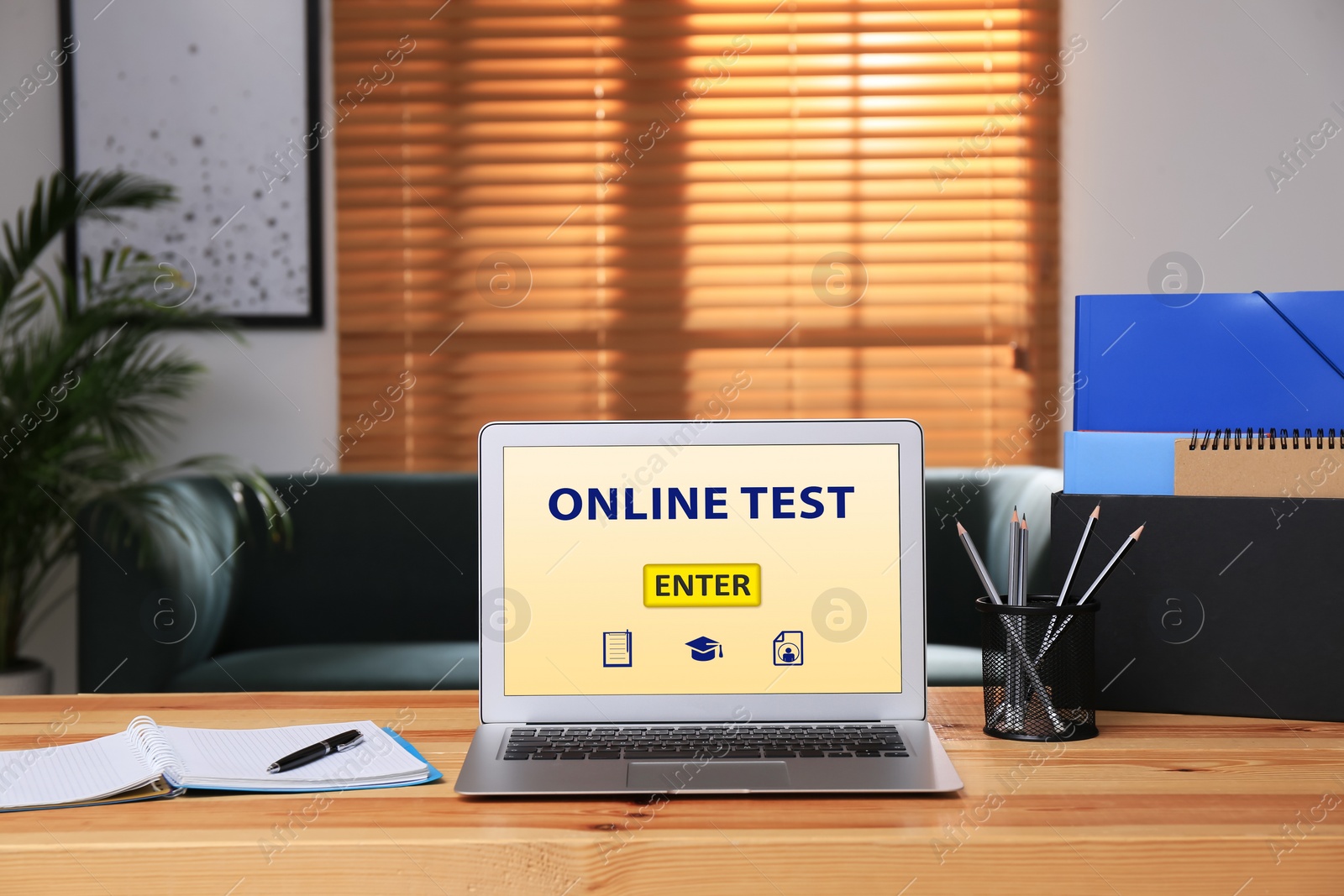 Photo of Laptop with online test and stationery on table in office