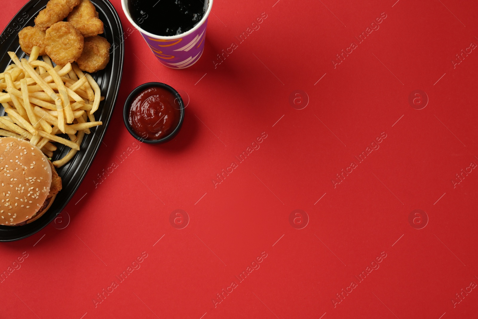 Photo of Different fast food on red background, flat lay. Space for text