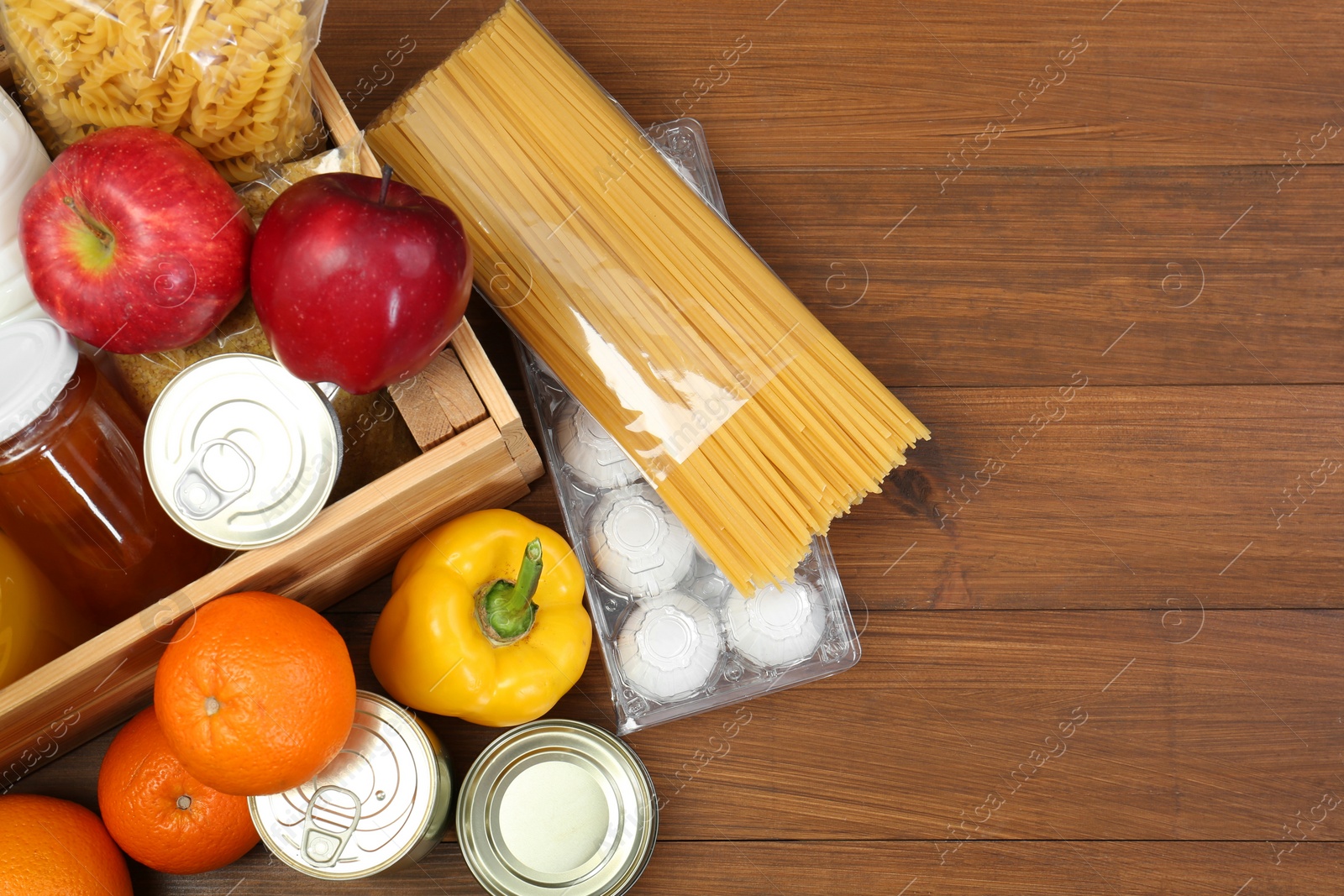 Photo of Humanitarian aid. Different food products for donation on wooden table, flat lay. Space for text