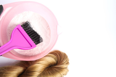 Photo of Strand of blond hair, bowl with dye and brush on white background, top view