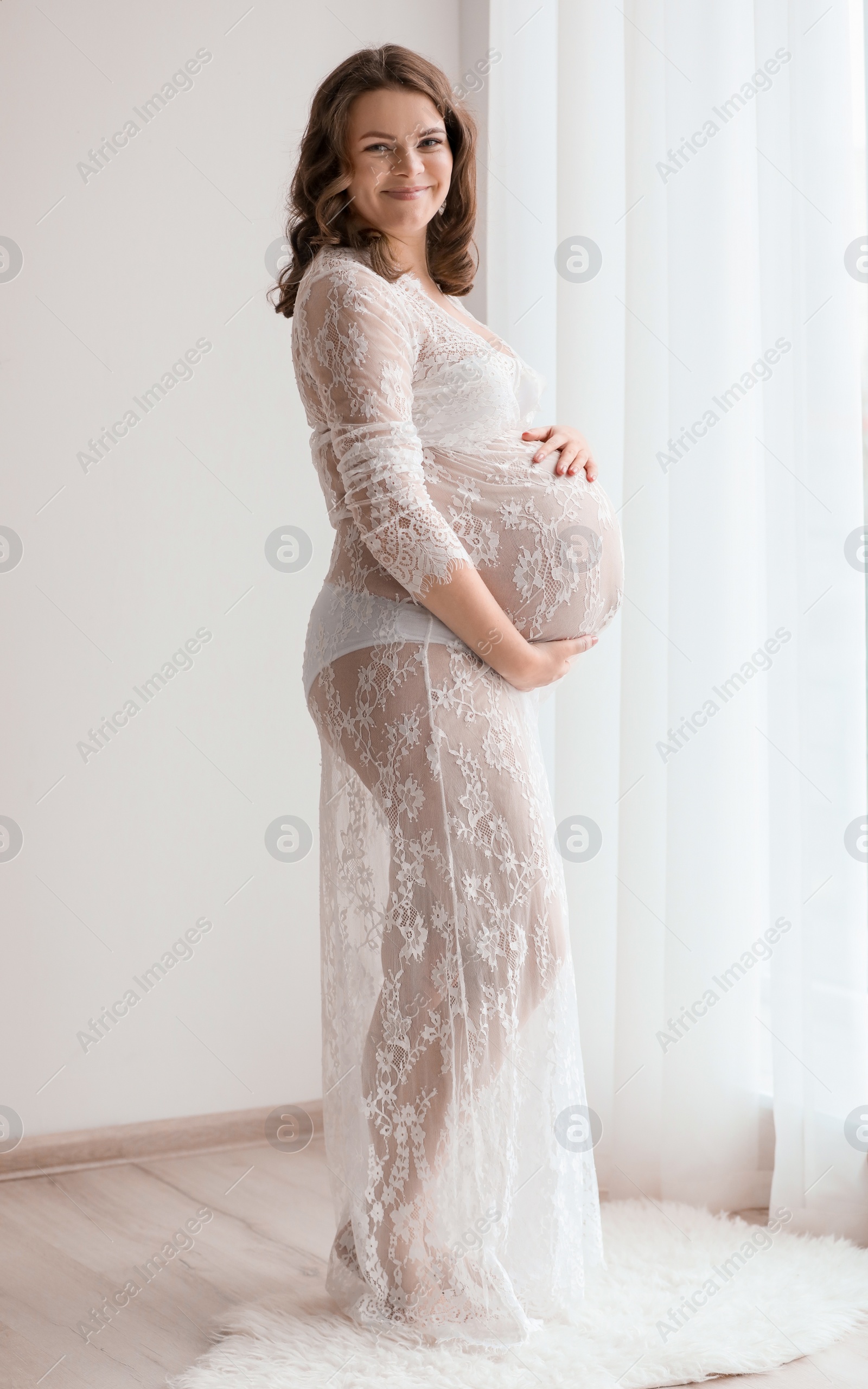 Photo of Young pregnant woman in elegant dress at home