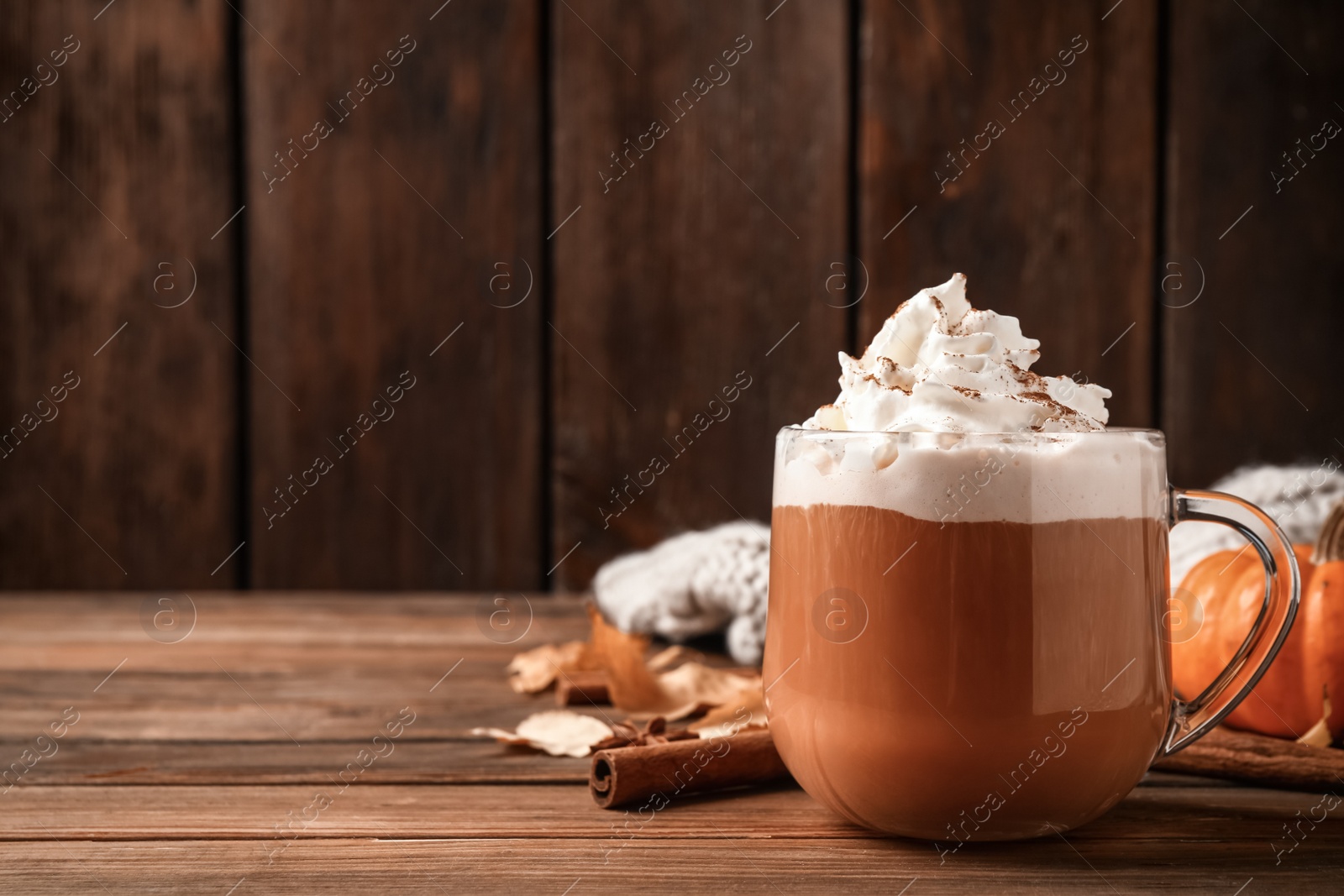 Photo of Delicious pumpkin latte on wooden table, closeup. Space for text