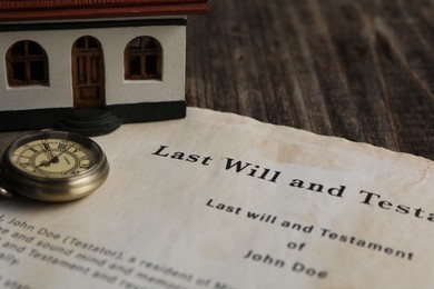 Photo of Last Will and Testament with pocket watch and house model on wooden table, closeup