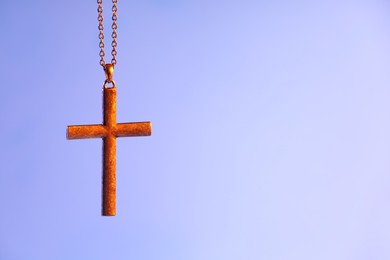 Photo of One cross with chain on violet background, space for text. Religion of Christianity