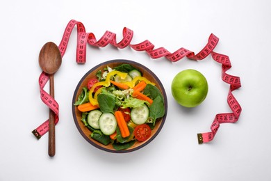 Measuring tape, salad, apple and spoon on white background, flat lay