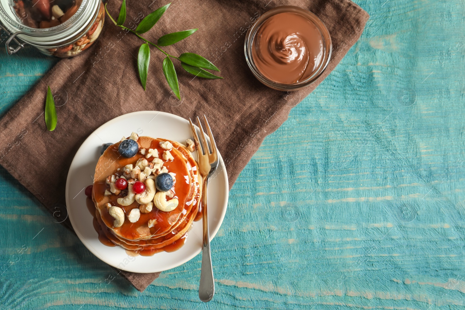 Photo of Tasty pancakes with berries, nuts and syrup on table, top view