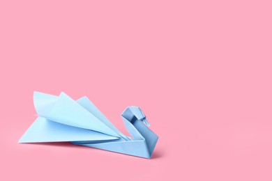 Photo of Origami art. Beautiful paper swan on pink background, space for text