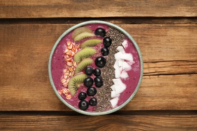Healthy breakfast with delicious acai smoothie and fruits in bowl on wooden table, top view