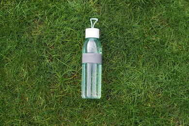 Photo of Bottle of water on green grass, top view. Morning exercise