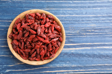 Dry goji berries on blue wooden table, top view. Space for text