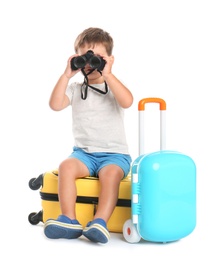 Cute little boy with binocular and suitcases on white background