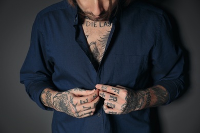 Young man with tattoos on body against black background, closeup