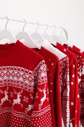 Rack with different Christmas sweaters on white background