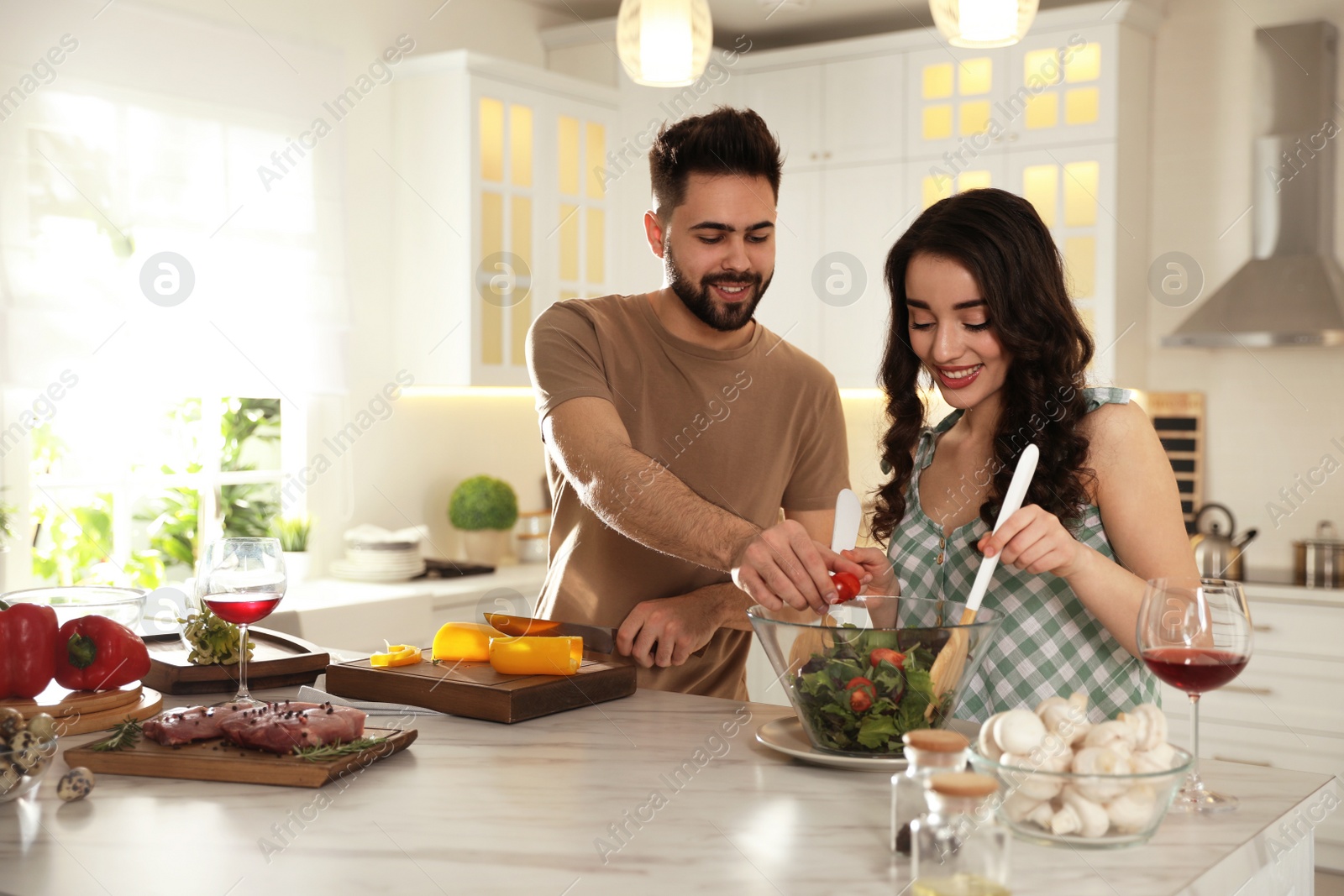 Photo of Lovely young couple cooking salad together in kitchen