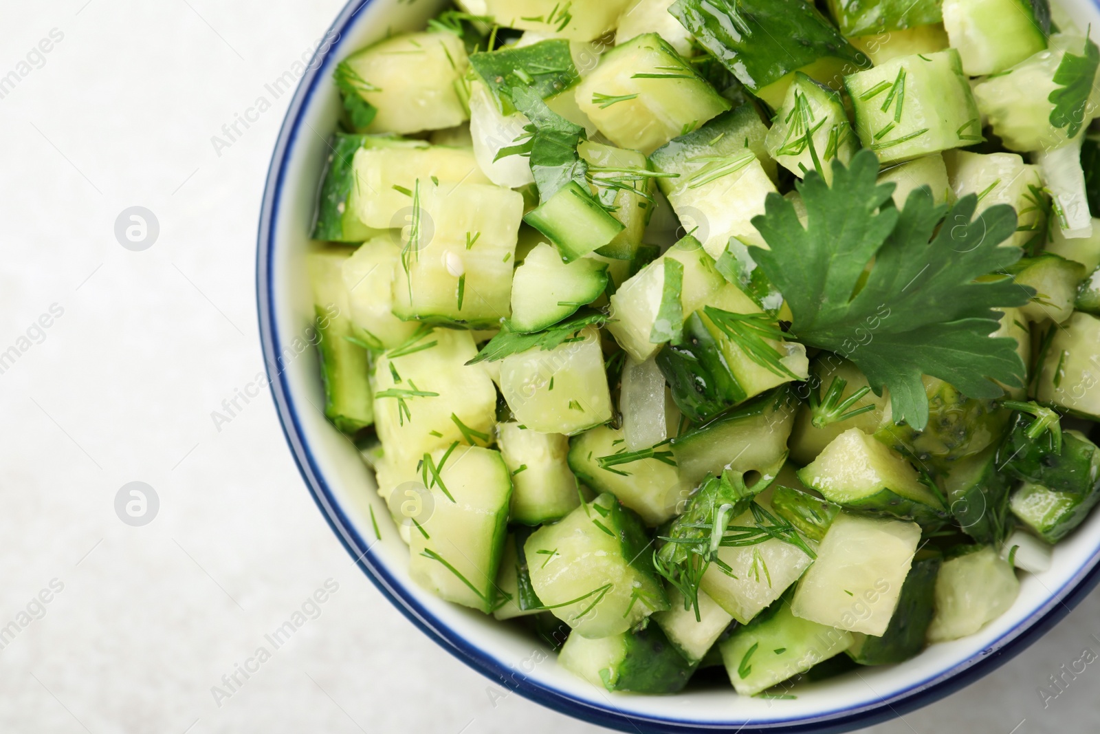 Photo of Bowl of delicious cucumber salad on light table, top view