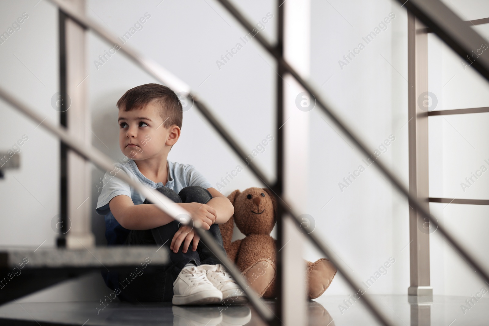 Photo of Sad little boy with toy sitting indoors