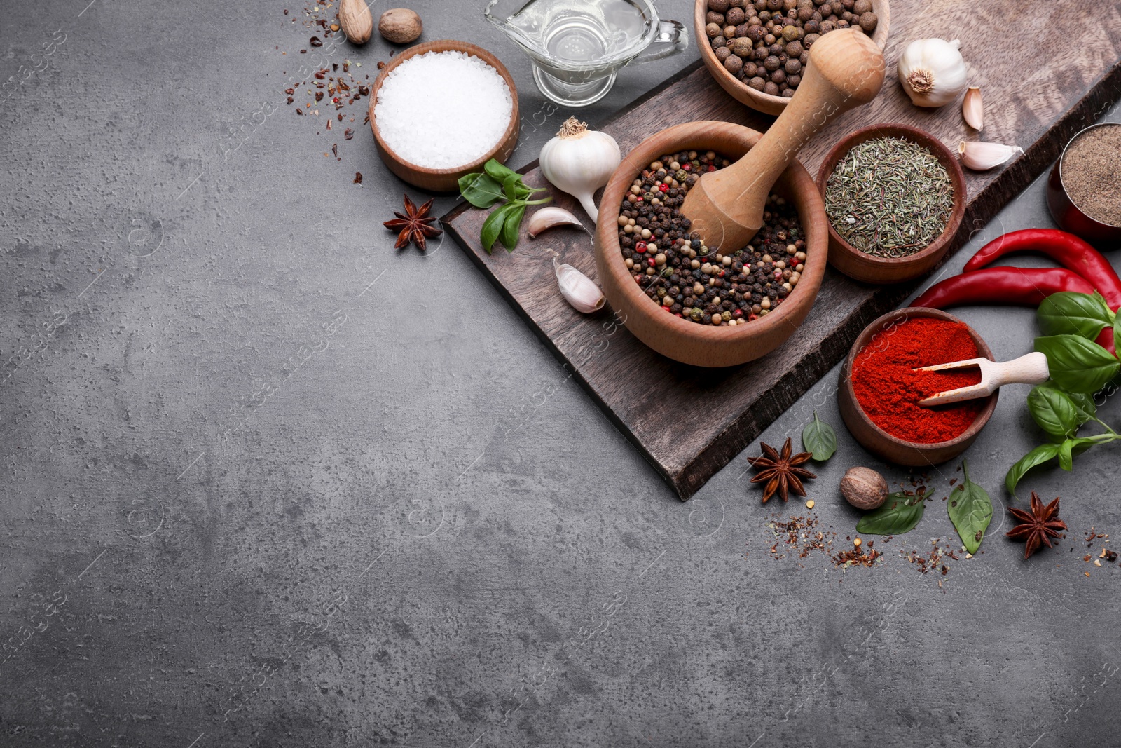 Photo of Mortar with different spices on grey table, flat lay. Space for text