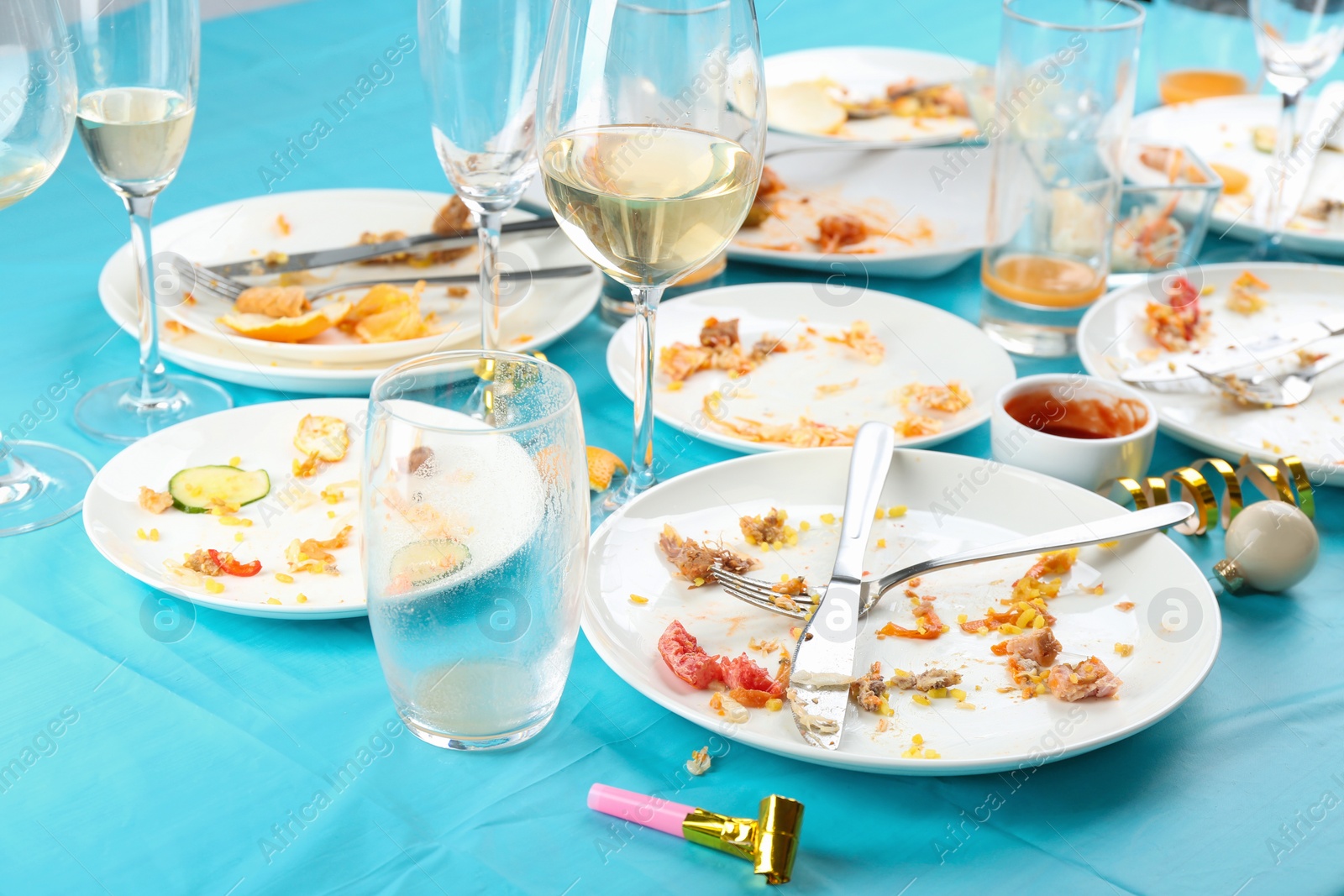 Photo of Dirty tableware with leftovers on light blue cloth after party