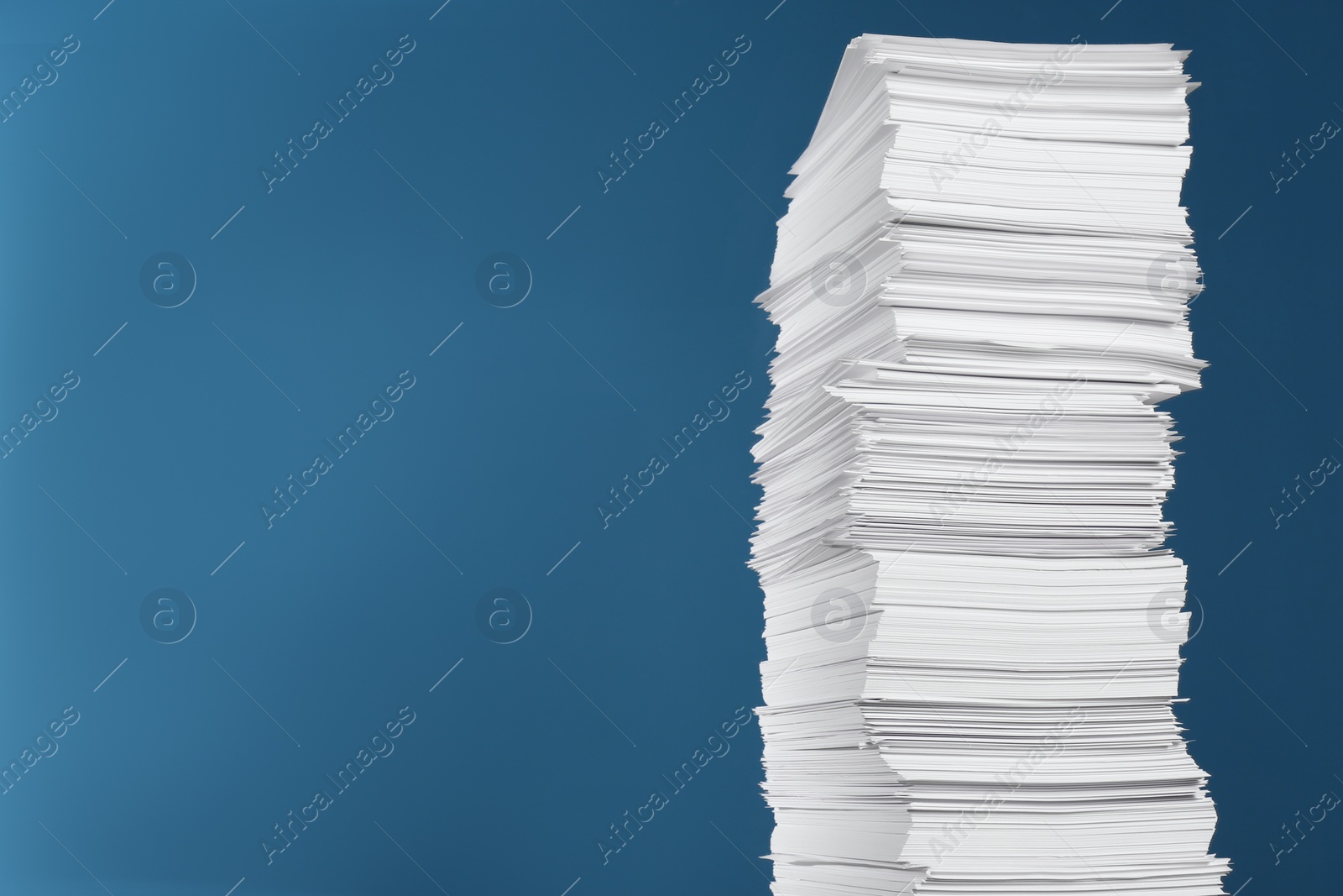 Photo of Stack of white paper sheets on blue background, space for text