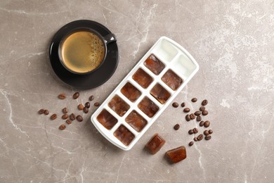 Photo of Ice cubes, cup of coffee and beans on grey table, flat lay